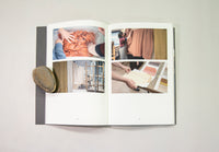 An open book displaying photographs of Clodagh Emoe's studio practice