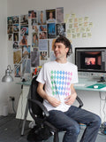 An artist wears a white t-shirt with a repeat diamond pattern in a rainbow gradient